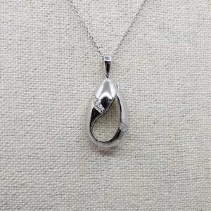 Può includere: Una collana con un ciondolo in argento dal design unico a forma di lacrima. Il ciondolo presenta un piccolo gruppo di diamanti trasparenti.