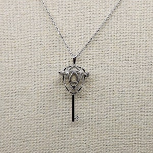 May include: A silver key-shaped pendant necklace with a cage-like design. The cage is made of delicate, intertwined metal wires, creating a geometric pattern.