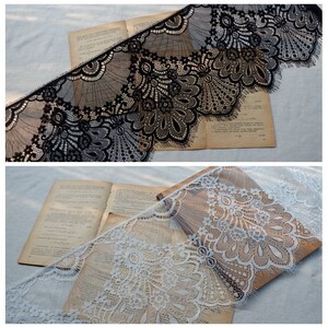 May include: Two pieces of black and white lace trim with scalloped edges. The lace is delicate and intricate with a floral pattern.