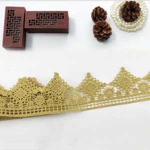 Puede incluir: Borde de encaje dorado con un delicado y complejo patrón. El encaje tiene un borde festoneado y es perfecto para agregar un toque de elegancia a cualquier proyecto.