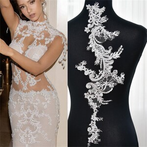Peut inclure: Applique en dentelle blanche avec un motif floral. L'applique est parfaite pour ajouter une touche d'élégance à n'importe quel vêtement.