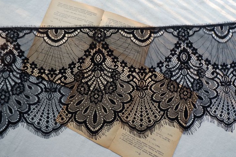 May include: Black lace trim with a delicate floral pattern. The lace has a scalloped edge and is perfect for adding a touch of elegance to any project.
