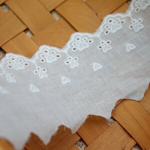 Peut inclure: Bordure en dentelle de coton blanche avec un bord festonn&eacute; et un motif floral d&eacute;licat. La dentelle mesure environ 2,5 cm de large.