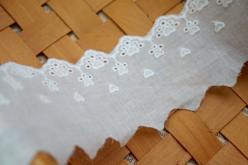 Peut inclure: Bordure en dentelle de coton blanche avec un bord festonn&eacute; et un motif floral d&eacute;licat. La dentelle mesure environ 2,5 cm de large.