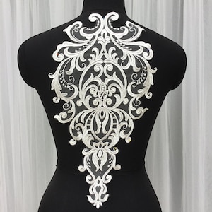 Op de afbeelding: Witte kant applique met een delicaat bloemenmotief. De applique is perfect om een ​​toets van elegantie toe te voegen aan elk kledingstuk.