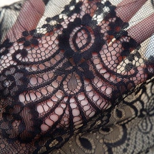 May include: Black lace fabric with a delicate floral pattern. The lace is soft and sheer, and it would be perfect for a variety of projects, such as clothing, accessories, and home decor.