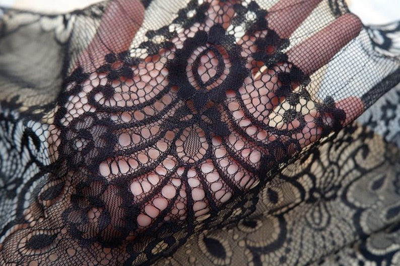 May include: Black lace fabric with a delicate floral pattern. The lace is soft and sheer, and it would be perfect for a variety of projects, such as clothing, accessories, and home decor.