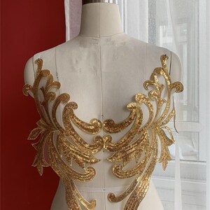 May include: Gold sequined applique with a floral design. The applique is on a sheer mesh fabric.