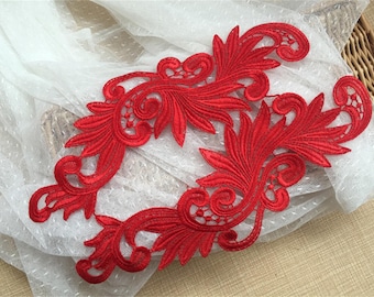 May include: Two red lace appliques with a floral design. The appliques are delicate and intricate, with a scalloped edge.