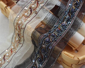 May include: Two beaded trims, one in black and one in beige, with gold and red accents. The trims are made of sequins, beads, and thread.
