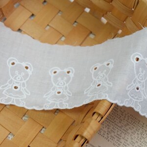 Peut inclure: Galon de dentelle en coton blanc avec un bord festonn&eacute; et un motif r&eacute;p&eacute;t&eacute; d'ours en peluche brod&eacute;s.