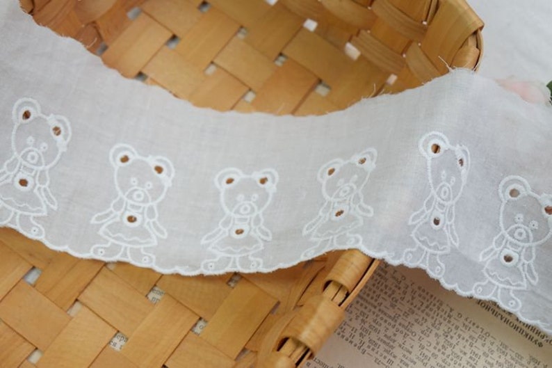 Peut inclure: Galon de dentelle en coton blanc avec un bord festonn&eacute; et un motif r&eacute;p&eacute;t&eacute; d'ours en peluche brod&eacute;s.