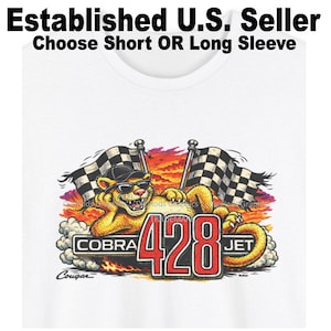May include: A white t-shirt featuring a graphic of a yellow cougar wearing sunglasses and a black cap, reclining in front of two checkered racing flags. The text reads Established U.S. Seller, Choose Short OR Long Sleeve, COBRA 428 JET, and Cougar.