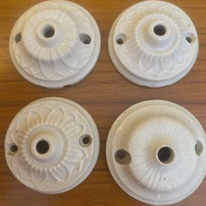 Puede incluir: Una taza de cerámica blanca con asa negra y el texto "But First, Coffee" en negrita negra. La taza se encuentra sobre un fondo borroso, sugiriendo un ambiente acogedor.