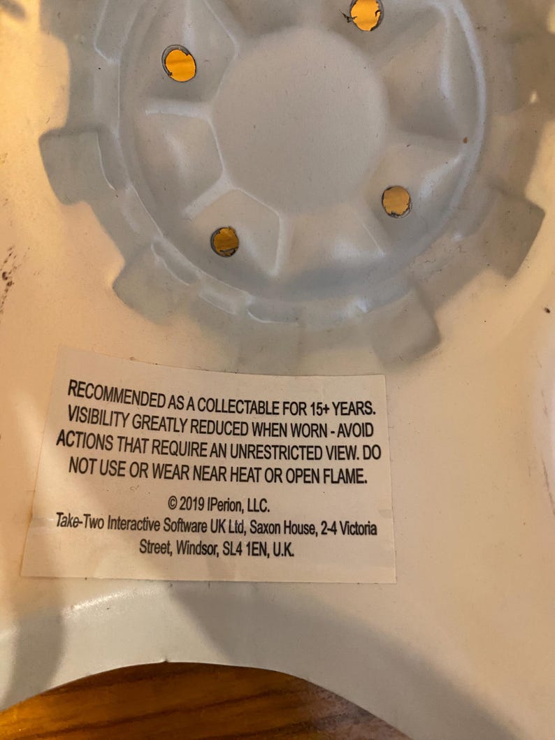 May include: White plastic collectible toy helmet with a warning label that reads: RECOMMENDED AS A COLLECTABLE FOR 15+ YEARS. VISIBILITY GREATLY REDUCED WHEN WORN - AVOID ACTIONS THAT REQUIRE AN UNRESTRICTED VIEW. DO NOT USE OR WEAR NEAR HEAT OR OPEN FLAME. &copy;2019 IPerion, LLC. Take-Two Interactive Software UK Ltd, Saxon House, 2-4 Victoria Street, Windsor, SL4 1EN, U.K.