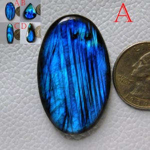 Op de afbeelding: Ovaalvormige blauwe labradorit edelsteen met iriserende kleurflitsen. De edelsteen is ongeveer zo groot als een Amerikaanse kwart.