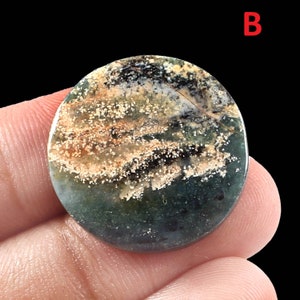 K&ouml;nnte beinhalten: Ein runder, gr&uuml;ner, brauner und wei&szlig;er Achat-Cabochon mit einem gesprenkelten Muster.