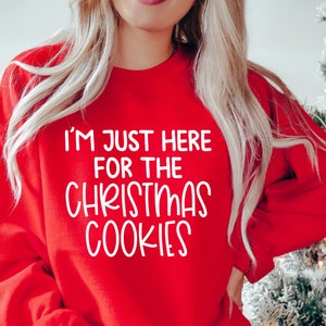 Peut inclure: Sweat-shirt rouge de No&euml;l avec un texte blanc qui dit "Je suis juste l&agrave; pour les biscuits de No&euml;l".