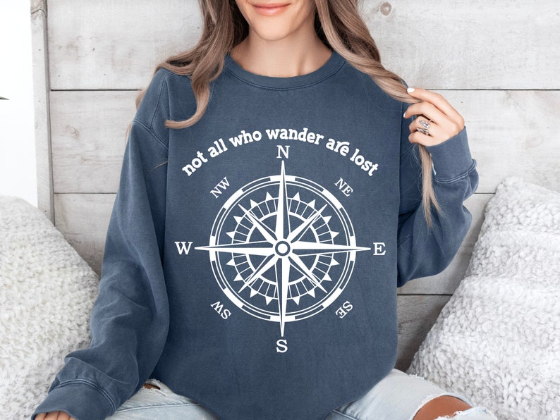 May include: A navy blue sweatshirt with the text "not all who wander are lost" and a compass graphic in white.