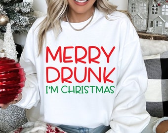 May include: White sweatshirt with the text "MERRY DRUNK I'M CHRISTMAS" in red and green lettering. The sweatshirt is a crew neck style, perfect for the holiday season. The design is festive and fun, ideal for Christmas gatherings.