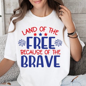 K&ouml;nnte beinhalten: Wei&szlig;es T-Shirt mit einer rot-wei&szlig;-blauen Grafik, auf der "Land of the Free Because of the Brave" steht. Die Grafik enth&auml;lt Sterne und Feuerwerk.