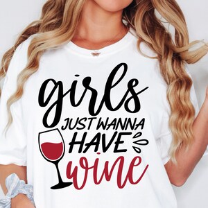 Puede incluir: Una camiseta blanca con texto en negro y rojo que dice "girls JUST WANNA HAVE wine" junto a un gr&aacute;fico de una copa de vino llena de l&iacute;quido rojo. El dise&ntilde;o est&aacute; centrado en la zona del pecho de la prenda y utiliza una mezcla de fuentes.