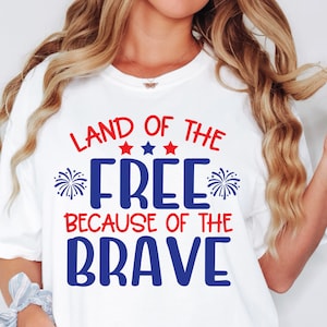 K&ouml;nnte beinhalten: Wei&szlig;es T-Shirt mit rotem und blauem Text, der "Land of the Free Because of the Brave" lautet. Der Text ist von roten Sternen und blauen Feuerwerksk&ouml;rpern umgeben.