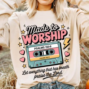 May include: A beige sweatshirt with a pink and blue cassette tape graphic. The text "Made to Worship" is above the cassette tape and the text "PSALMS 150:6" is on the cassette tape. The text "Let everything that has breath praise the Lord" is below the cassette tape.