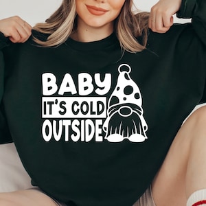 May include: A dark green sweatshirt with white text that reads "Baby It's Cold Outside" and a white gnome graphic.