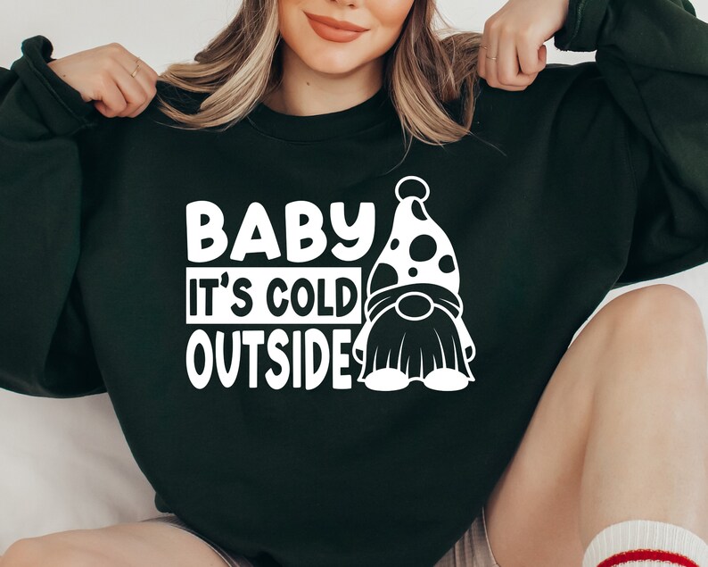 May include: A dark green sweatshirt with white text that reads "Baby It's Cold Outside" and a white gnome graphic.