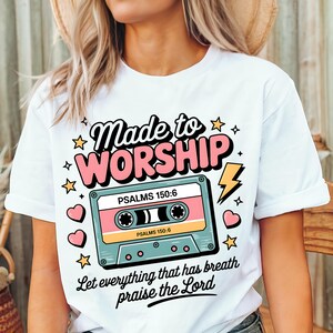 May include: White t-shirt with a pink and blue cassette tape graphic. The text "Made to Worship" is above the cassette tape and the text "PSALMS 150:6" is on the cassette tape. The text "Let everything that has breath praise the Lord" is below the cassette tape.
