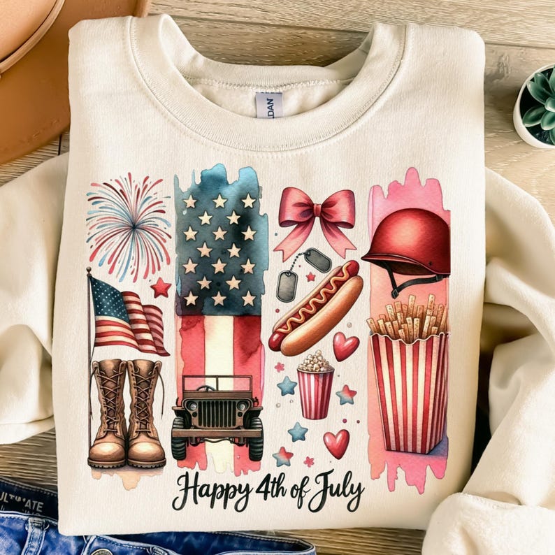 K&ouml;nnte beinhalten: Ein beiger Pullover mit einem grafischen Design, das eine Aquarell-Illustration amerikanischer patriotischer Symbole zeigt, darunter Feuerwerk, eine Flagge, einen Jeep, einen Hotdog, Popcorn, Pommes Frites, eine Schleife und einen Milit&auml;rhelm. Der Text "Happy 4th of July" ist unter dem Grafikdruck.