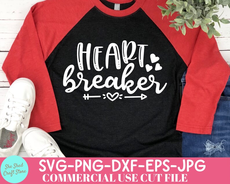 May include: A black and red raglan shirt with the words "Heartbreaker" in white script. The design includes hearts and an arrow. The shirt is paired with white sneakers and blue jeans.