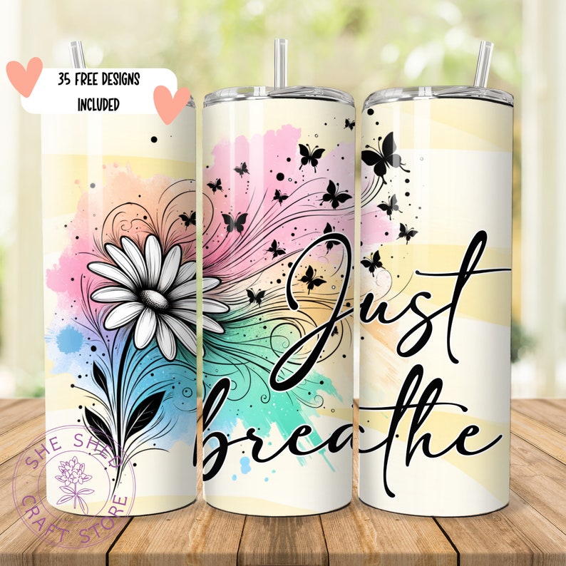 May include: A white tumbler with a watercolor design of a daisy and butterflies. The text "Just Breathe" is written in black on the tumbler.