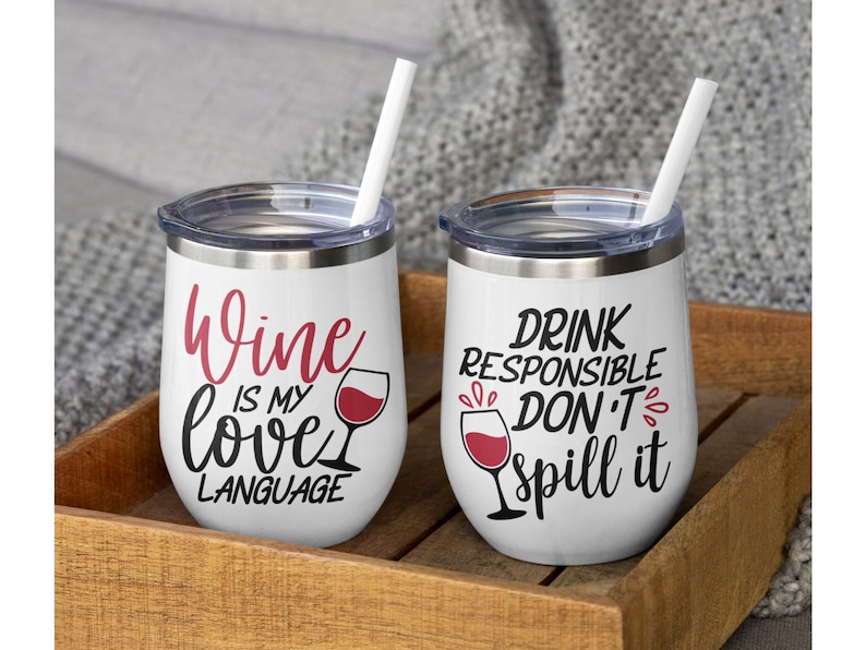 Puede incluir: Dos vasos blancos de acero inoxidable con tapas transparentes y pajitas blancas. El vaso izquierdo tiene texto en rojo y negro que dice Wine is my love language con un icono de copa de vino. El derecho tiene texto en negro y rojo que dice DRINK RESPONSIBLE DON'T spill it con un icono de copa de vino.