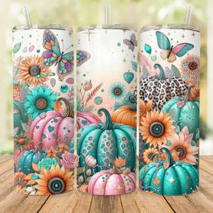 May include: Three stainless steel tumblers with a fall-themed design. The tumblers feature a pink, teal, and orange color scheme with pumpkins, butterflies, sunflowers, and glitter accents.