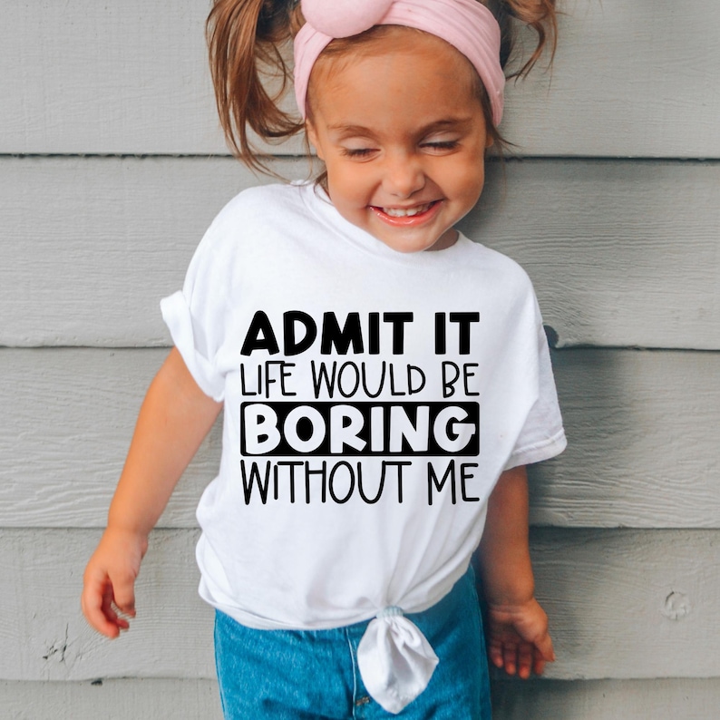 May include: A white short-sleeved t-shirt featuring black text that reads ADMIT IT LIFE WOULD BE BORING WITHOUT ME, with the word BORING enclosed in a black rectangular box. The shirt is styled with a knotted hem at the bottom front.