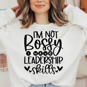 May include: White sweatshirt with black text that reads "I'm not bossy I have leadership skills" with hearts on either side of the word "skills".