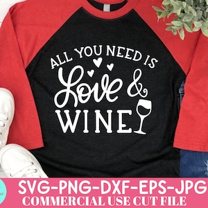 May include: A black and red raglan shirt with the text "ALL YOU NEED IS Love & WINE" in white script. The shirt features a wine glass graphic and is paired with white sneakers and blue jeans.