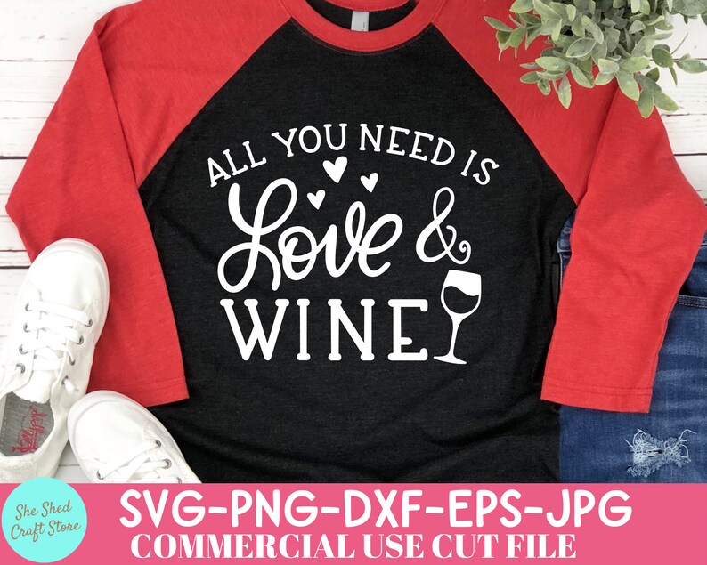 May include: A black and red raglan shirt with the text "ALL YOU NEED IS Love & WINE" in white script. The shirt features a wine glass graphic and is paired with white sneakers and blue jeans.