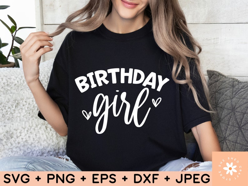 May include: A black t-shirt with the text "Birthday girl" in white lettering with two small hearts on either side of the word "girl".