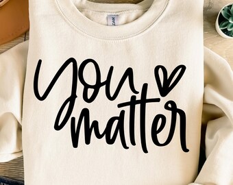 Puede incluir: Una sudadera de color crema con el texto "you matter" en letra negra con un pequeño símbolo de corazón.
