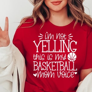 May include: Red t-shirt with white text that reads "I'm not yelling this is my basketball mom voice" and a white basketball graphic.