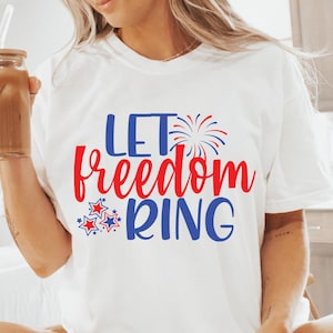 May include: White t-shirt with the text "Let freedom ring" in red and blue lettering. The text is surrounded by red and blue stars and a blue firework graphic.
