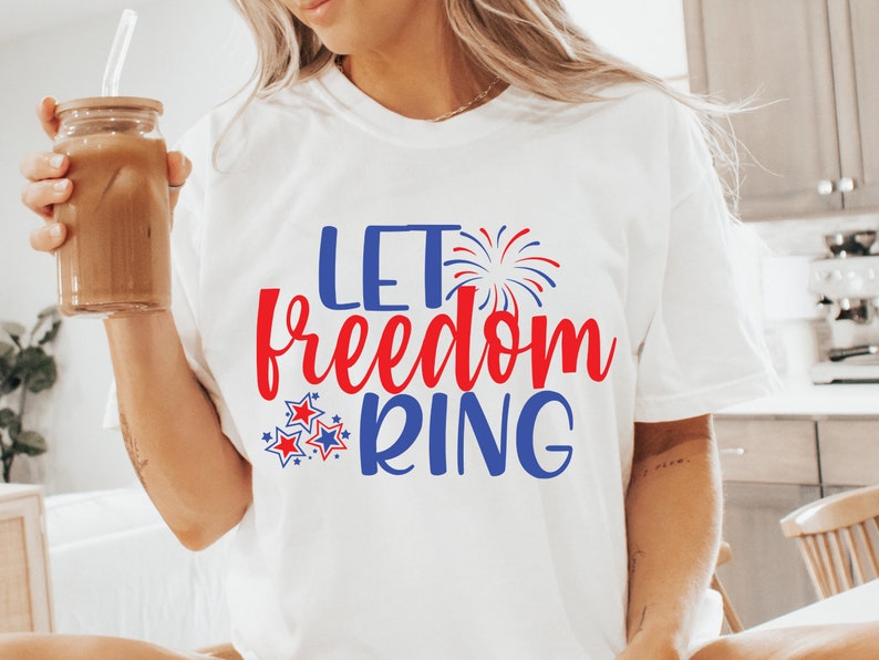 May include: White t-shirt with the text "Let freedom ring" in red and blue lettering. The text is surrounded by red and blue stars and a blue firework graphic.