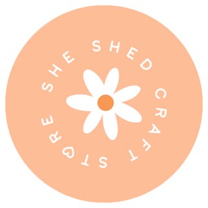 May include: A peach-colored circle with the text "She Shed Crafts" in white lettering around a white daisy with a yellow center.
