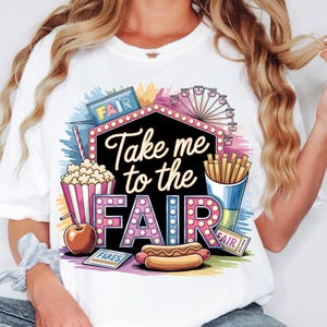 May include: White t-shirt with a colorful graphic design featuring the text "Take me to the Fair" in a marquee style. The graphic also includes a Ferris wheel, popcorn, hot dog, french fries, and a ticket that says "Fair".