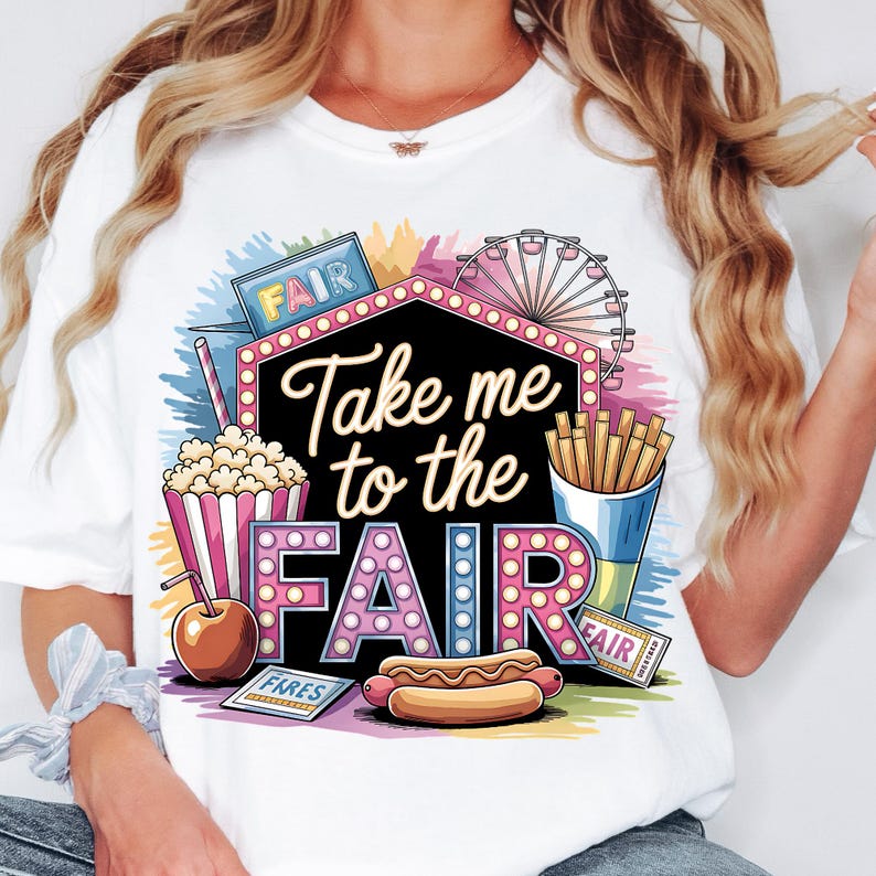 May include: White t-shirt with a colorful graphic design featuring the text "Take me to the Fair" in a marquee style. The graphic also includes a Ferris wheel, popcorn, hot dog, french fries, and a ticket that says "Fair".