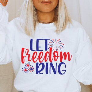 May include: White sweatshirt with the text "Let freedom ring" in red and blue lettering. The text is surrounded by red and blue stars and a firework graphic.