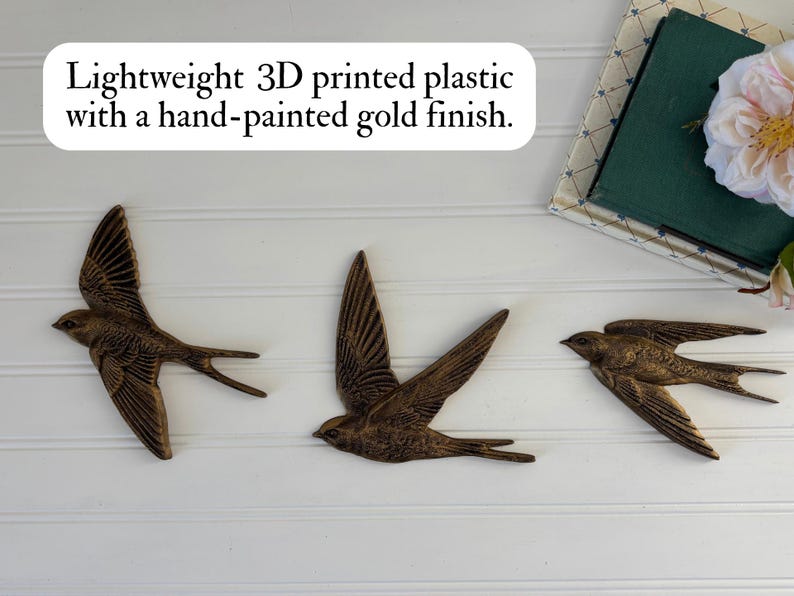 May include: Three lightweight, 3D-printed plastic swallows with a hand-painted gold finish are displayed against a white background. The swallows are in mid-flight, with their wings spread. The text in the image says: Lightweight 3D printed plastic with a hand-painted gold finish.